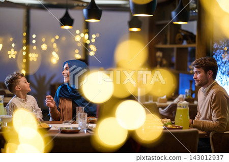 Family Dinner Celebration in Restaurant With Woman in Hijab Sharing Laughs and Festive Lights Family Dinner Celebration in Restaurant With Woman in Hijab Sharing Laughs and Festive Lights 143012937