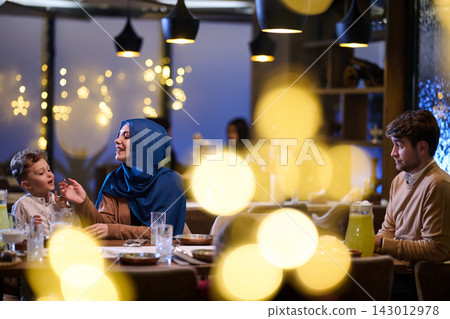 Muslim Family Enjoying Warm Restaurant Dinner Together Under Festive Lights During Evening Celebration Muslim Family Enjoying Warm Restaurant Dinner Together Under Festive Lights During Evening Celebration 143012978