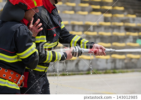 Firefighters Training With Hose Streaming Water During Outdoor Emergency Drill At Stadium Firefighters Training With Hose Streaming Water During Outdoor Emergency Drill At Stadium 143012985
