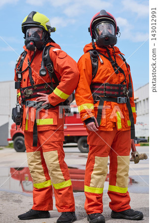 Two Firefighters in Full Protective Gear With Masks and Helmets Standing Confidently by Fire Truck Two Firefighters in Full Protective Gear With Masks and Helmets Standing Confidently by Fire Truck 143012991