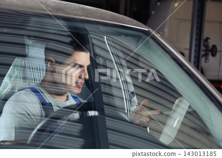 Mechanic with laptop doing car diagnostic at automobile repair shop Mechanic with laptop doing car diagnostic at automobile repair shop 143013185
