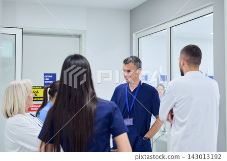 Group of medical professionals discussing patient care strategies in a hospital setting during daytime hours Group of medical professionals discussing patient care strategies in a hospital setting during daytime hours 143013192
