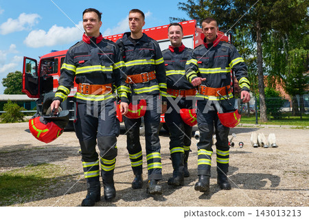 Four Firefighters Walking Confidently in Uniform With Helmets and Fire Truck in Background Four Firefighters Walking Confidently in Uniform With Helmets and Fire Truck in Background 143013213