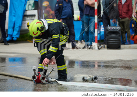 Firefighter Connecting Hose to Hydrant During Outdoor Emergency Response Training Exercise With Spectators Firefighter Connecting Hose to Hydrant During Outdoor Emergency Response Training Exercise With Spectators 143013236