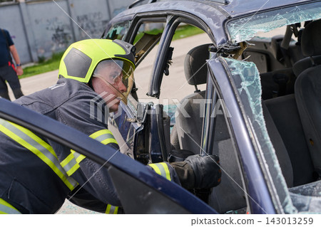 Firefighter Performing Vehicle Rescue Extraction With Hydraulic Tool At Car Accident Scene Firefighter Performing Vehicle Rescue Extraction With Hydraulic Tool At Car Accident Scene 143013259