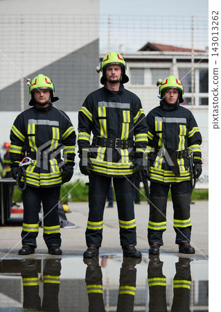 Three Firefighters Standing in Full Protective Gear With Reflective Stripes and Helmets Three Firefighters Standing in Full Protective Gear With Reflective Stripes and Helmets 143013262