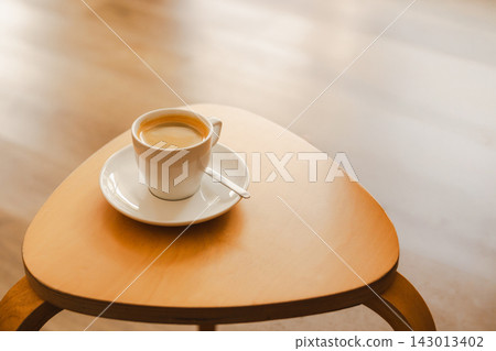 Cup of freshly hot espresso with delicate crema on a small wooden table in a cozy cafe. Cup of freshly hot espresso with delicate crema on a small wooden table in a cozy cafe. 143013402