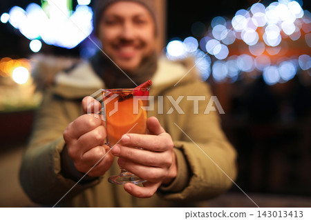Happy man with mulled wine at winter fair, focus on hands Happy man with mulled wine at winter fair, focus on hands 143013413