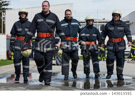 Firefighters Walking Through Water After Drill Team of Firefighters in Full Protective Gear 143013591
