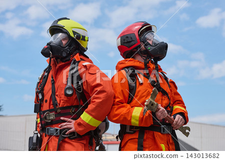 Two Firefighters in Orange Protective Gear Wearing Helmets and Breathing Masks Ready for Rescue 143013682
