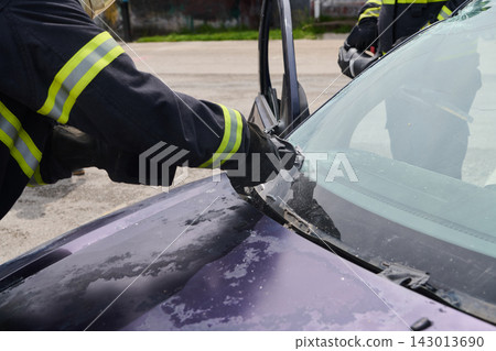 Firefighter Rescue Team Using Hydraulic Cutter For Vehicle Extrication And Windshield Removal At Accident Scene Firefighter Rescue Team Using Hydraulic Cutter For Vehicle Extrication And Windshield Removal At Accident Scene 143013690