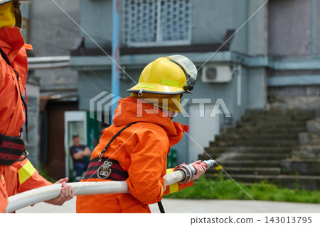 Firefighter Team Training With Hose During Urban Firefighting Drill Wearing Yellow Helmets Firefighter Team Training With Hose During Urban Firefighting Drill Wearing Yellow Helmets 143013795