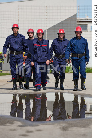 Firefighters Team Walking Together In Uniform With Red Helmets And Puddle Reflection 143013812
