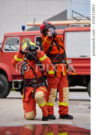 Two Firefighters In Protective Gear With Fire Truck Pointing And Using Binoculars During Rescue Training Two Firefighters In Protective Gear With Fire Truck Pointing And Using Binoculars During Rescue Training 143013863