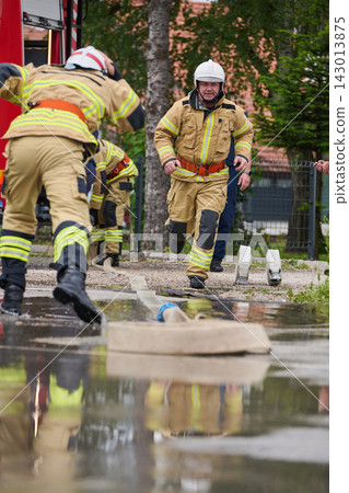 Firefighters Running to Scene During Training Exercise With Fire Hose and Equipment Firefighters Running to Scene During Training Exercise With Fire Hose and Equipment 143013875