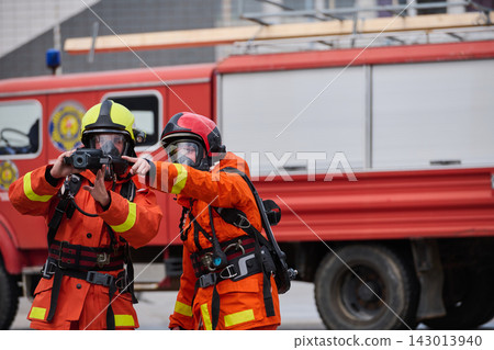 Firefighters In Protective Gear Using Thermal Camera By Red Fire Truck During Emergency Response Training Firefighters In Protective Gear Using Thermal Camera By Red Fire Truck During Emergency Response Training 143013940
