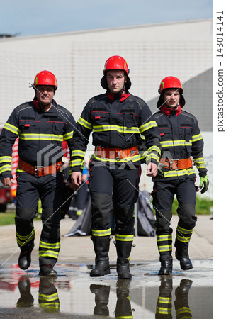 Three Firefighters in Protective Gear Walking Confidently After Emergency Response Training Drill Three Firefighters in Protective Gear Walking Confidently After Emergency Response Training Drill 143014141