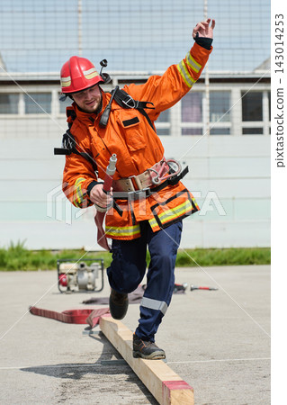 Firefighter Training Balance Drill With Hose And Safety Gear During Outdoor Rescue Exercise Firefighter Training Balance Drill With Hose And Safety Gear During Outdoor Rescue Exercise 143014253