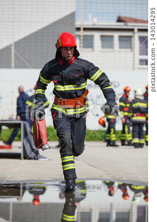 Firefighter Running With Hose During Training Drill Wearing Protective Uniform And Red Helmet Firefighter Running With Hose During Training Drill Wearing Protective Uniform And Red Helmet 143014295