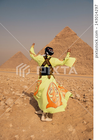 Traditional folk dancer in vibrant lime green and orange embroidered costume raises arms in joyful back view pose before the iconic twin Giza pyramids Traditional folk dancer in vibrant lime green and orange embroidered costume raises arms in joyful back view pose before the iconic twin Giza pyramids 143014297