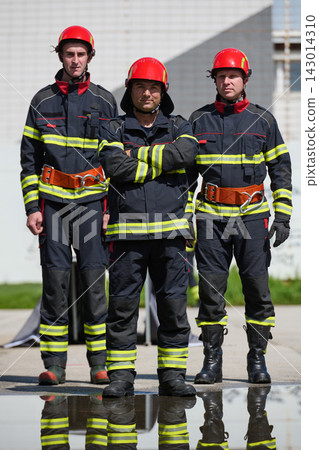 Three Firefighters In Full Gear Standing Confidently Outside Fire Station With Reflective Boots Three Firefighters In Full Gear Standing Confidently Outside Fire Station With Reflective Boots 143014310