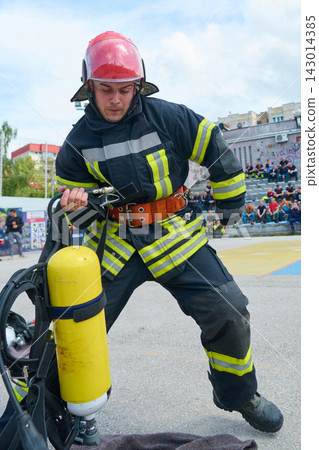 Firefighter Putting On Breathing Apparatus During Urban Training Drill With Yellow Oxygen Cylinder Firefighter Putting On Breathing Apparatus During Urban Training Drill With Yellow Oxygen Cylinder 143014385