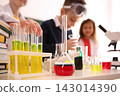 Smart pupils making experiment in chemistry class, focus on flask with reagent 143014390