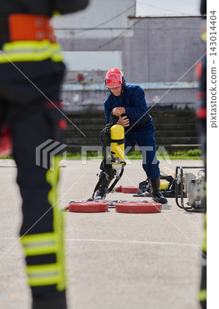 Firefighter Preparing Breathing Apparatus During Outdoor Training Drill With Red Helmet And Safety Gear Firefighter Preparing Breathing Apparatus During Outdoor Training Drill With Red Helmet And Safety Gear 143014404