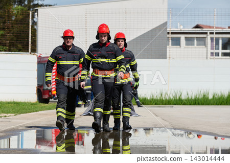 Firefighters Walking Together in Uniform With Red Helmets During Training or Emergency Response 143014444
