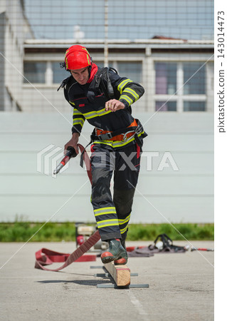Firefighter Training Exercise Balancing On Beam With Hose And Safety Gear During Drill 143014473