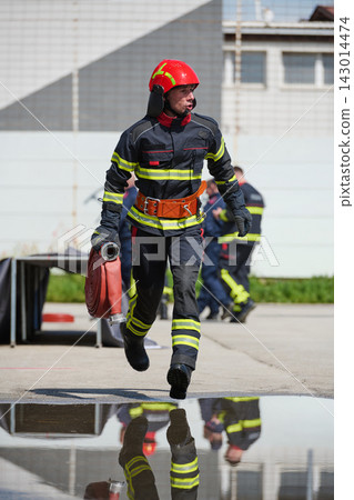 Firefighter Running With Hose During Emergency Drill Wearing Helmet And Reflective Protective Gear Firefighter Running With Hose During Emergency Drill Wearing Helmet And Reflective Protective Gear 143014474