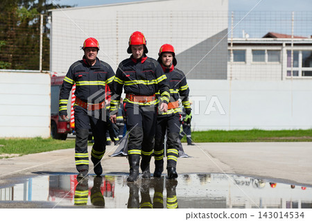 Firefighters Team Walking Toward Camera In Gear During Training Exercise Near Fire Truck Firefighters Team Walking Toward Camera In Gear During Training Exercise Near Fire Truck 143014534