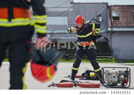 Firefighter Training Drill With Full Gear Putting On Breathing Apparatus Near Hoses And Pump Firefighter Training Drill With Full Gear Putting On Breathing Apparatus Near Hoses And Pump 143014551