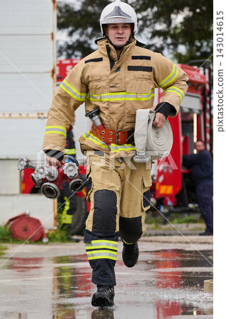 Firefighter Running With Hose And Valve Coupling During Emergency Response At Fire Station Firefighter Running With Hose And Valve Coupling During Emergency Response At Fire Station 143014615