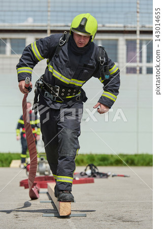 Firefighter Training Drill Running With Hose Wearing Helmet And Protective Gear During Rescue Exercise Firefighter Training Drill Running With Hose Wearing Helmet And Protective Gear During Rescue Exercise 143014655