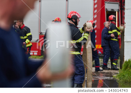 Firefighters Unrolling Hose Near Red Fire Truck During Emergency Response Training Firefighters Unrolling Hose Near Red Fire Truck During Emergency Response Training 143014743