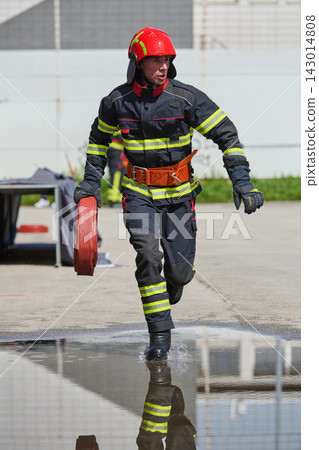 Firefighter Running With Hose And Water Reflection During Emergency Training Exercise Firefighter Running With Hose And Water Reflection During Emergency Training Exercise 143014808