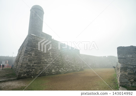 A tall stone sentry tower stands above the corner wall of Castillo de San Marcos. Heavy fog softens the historic fortress and creates a minimalist scene. 143014992