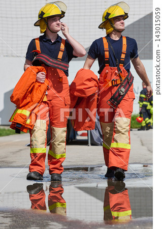 Two Firefighters in Orange Protective Gear Walking With Helmets During Training Drill Two Firefighters in Orange Protective Gear Walking With Helmets During Training Drill 143015059