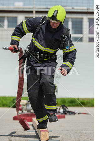 Firefighter in Full Gear Balancing on Beam While Carrying Hose During Training Exercise Firefighter in Full Gear Balancing on Beam While Carrying Hose During Training Exercise 143015094