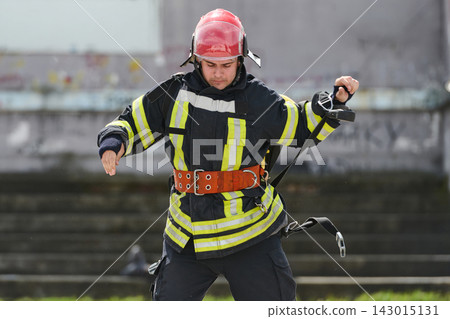 Firefighter In Full Gear With Helmet And Safety Belt Practicing Rescue Training Outdoors Firefighter In Full Gear With Helmet And Safety Belt Practicing Rescue Training Outdoors 143015131