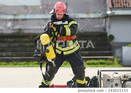 Firefighter Putting On Breathing Apparatus During Emergency Training Exercise With Full Protective Gear Firefighter Putting On Breathing Apparatus During Emergency Training Exercise With Full Protective Gear 143015133