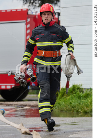 Firefighter Running With Hose And Hydrant Connector Near Fire Truck During Emergency Response Training Firefighter Running With Hose And Hydrant Connector Near Fire Truck During Emergency Response Training 143015138