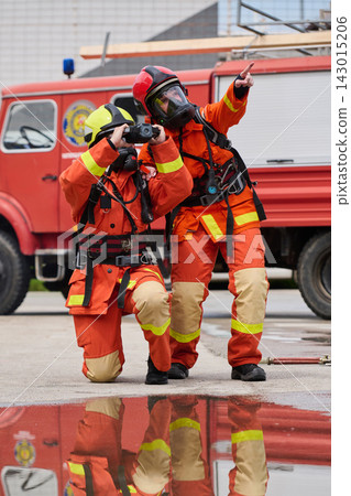 Two Firefighters in Protective Gear Using Binoculars Near Fire Truck During Emergency Response Two Firefighters in Protective Gear Using Binoculars Near Fire Truck During Emergency Response 143015206