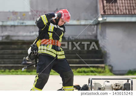 Firefighter In Full Gear Adjusting Helmet During Training Exercise With Rescue Equipment Outdoors 143015243