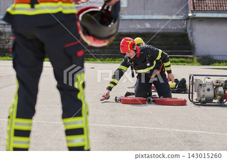 Firefighter Training Drill With Crew Rolling Hoses and Safety Gear During Outdoor Exercise Firefighter Training Drill With Crew Rolling Hoses and Safety Gear During Outdoor Exercise 143015260