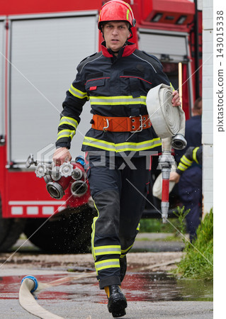 Firefighter Running With Rolled Hose And Manifold From Firetruck During Emergency Response Drill Firefighter Running With Rolled Hose And Manifold From Firetruck During Emergency Response Drill 143015338