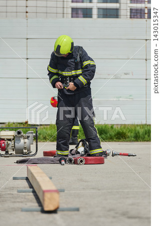 Firefighter Preparing Gear During Training Drill With Helmet Hose And Protective Uniform At Station Firefighter Preparing Gear During Training Drill With Helmet Hose And Protective Uniform At Station 143015347