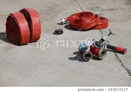 Rolled Red Fire Hoses and Multi Valve Hydrant Coupler Laid Out on Concrete at Fire Station Rolled Red Fire Hoses and Multi Valve Hydrant Coupler Laid Out on Concrete at Fire Station 143015527