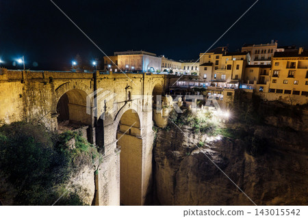 Puente Nuevo bridge glows above the illuminated cliffside restaurants of Ronda at night Puente Nuevo bridge glows above the illuminated cliffside restaurants of Ronda at night 143015542